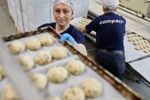 Mitarbeiterin aus der Produktion hält Blech mit Back-Teiglingen hoch.