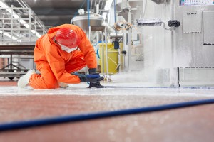 Ein*e Mitarbeiter*in reinigt mit einem Wasserschlauch und Schaum die Anlage.